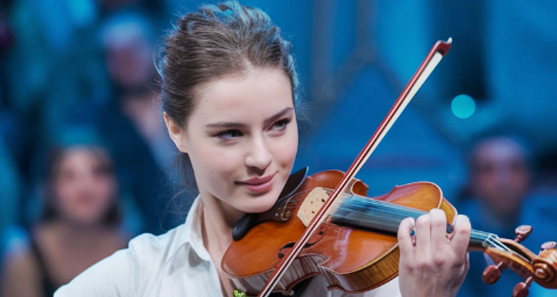 A lady named Gabriella walks on Americas Got Talent stage, introduces herself and tells the audience she is going to play the violin